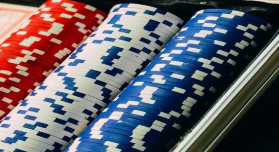 Close-up of red, white, and blue poker chips stacked in a tray on a casino table.