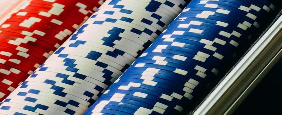 Close-up of red, white, and blue poker chips stacked in a tray on a casino table.