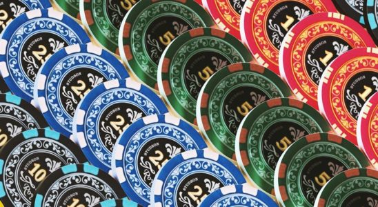 Pile of colorful poker chips in blue, green, red, and black showing denominations of 2, 5, and 10.