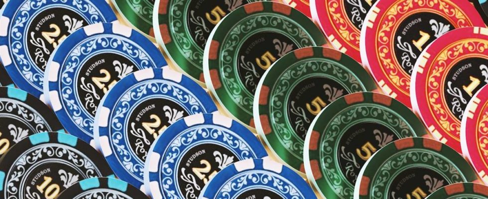 Pile of colorful poker chips in blue, green, red, and black showing denominations of 2, 5, and 10.